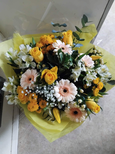 Spring day - yellow, peach and white flowers presented in an aqua pack in a box or bag - some flowers may be subsituted depending upon season